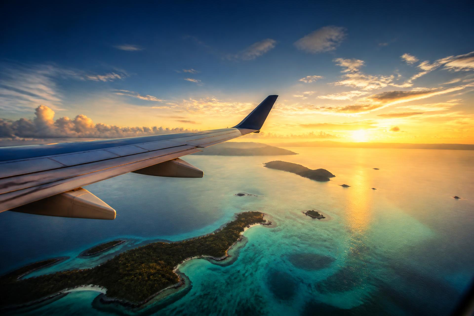 Ala de avión sobre islas del Caribe al atardecer